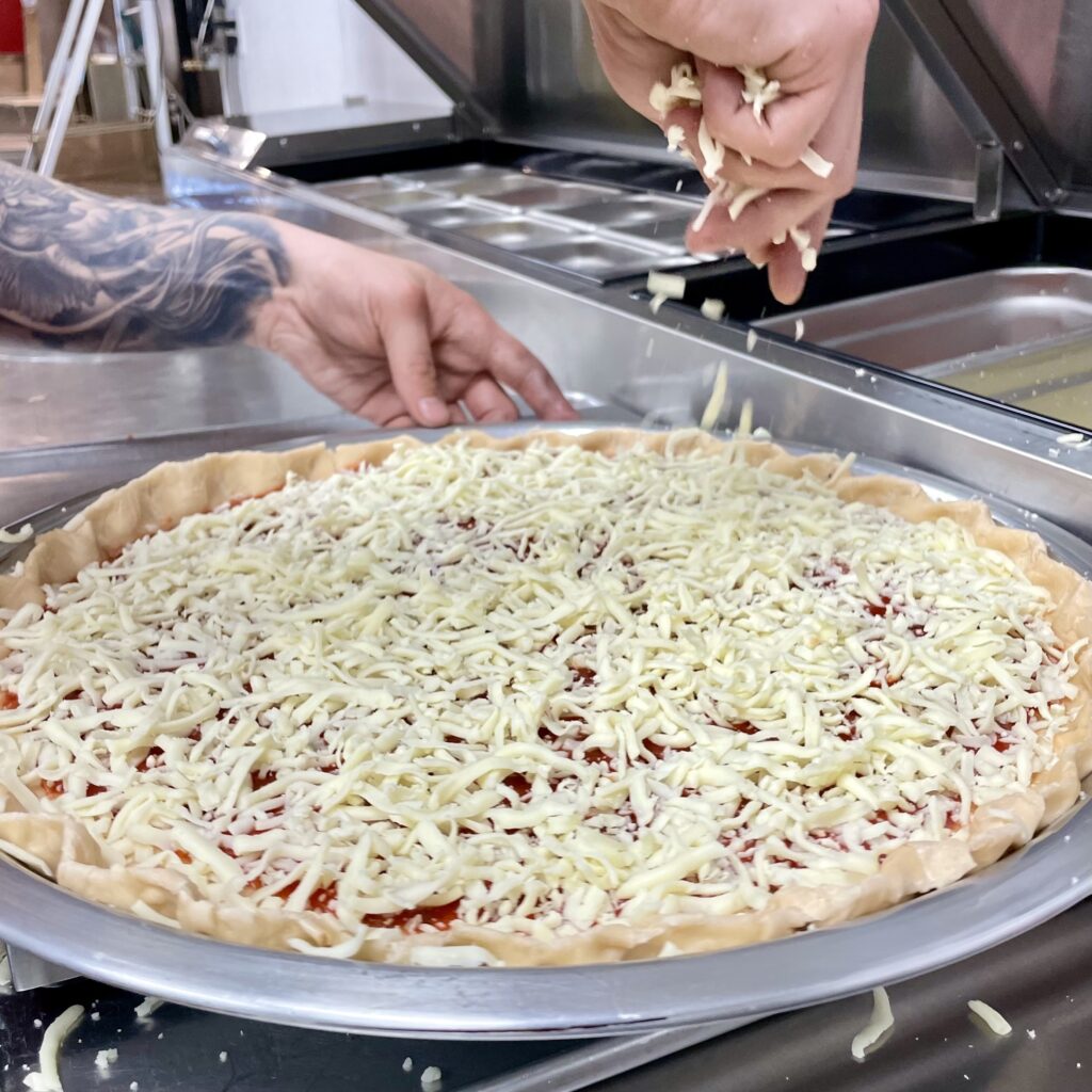 Rascal House Downtown Cleveland 5 Sprinkling cheese on pizza